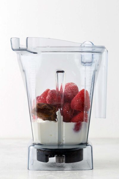 Strawberries, date, yogurt, and milk in a blender. 