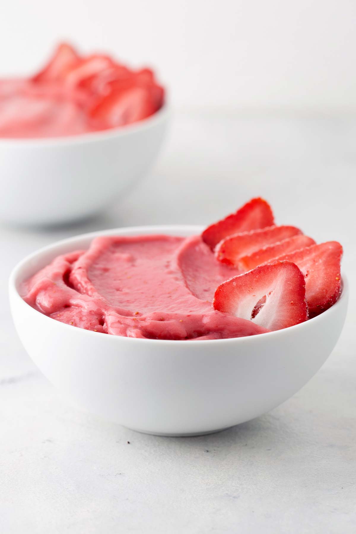 Strawberry smoothie bowl with sliced strawberries on top.