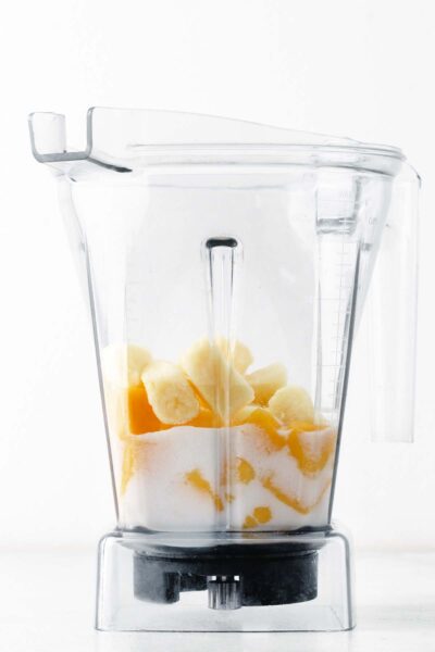 Frozen pineapple in blender with milk and mango.