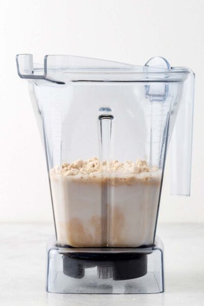 Vanilla protein, vanilla extract, date syrup, and almond milk in a blender.